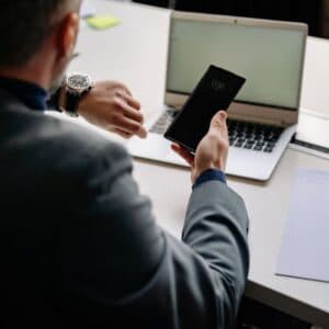 Man in office using smartphone and laptop